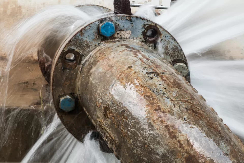 Close-up of old, rusted water pipe leaking at joint.